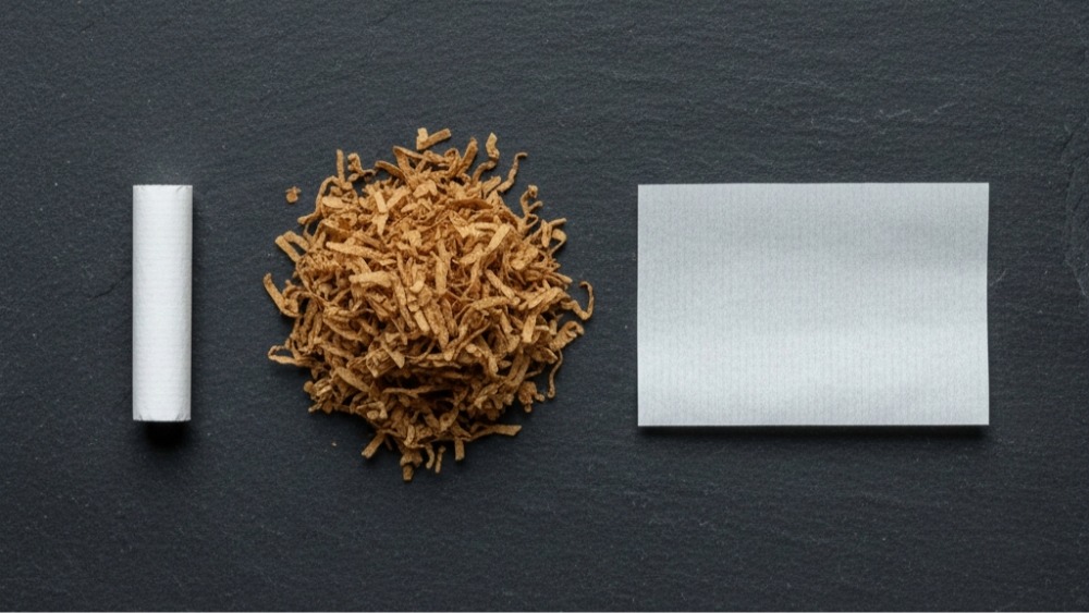 Cigarette anatomy components showing white filter, loose tobacco blend, and rolling paper on dark background