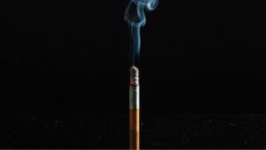 Burning cigarette with smoke demonstrating tobacco combustion and chemical compound release during smoking process